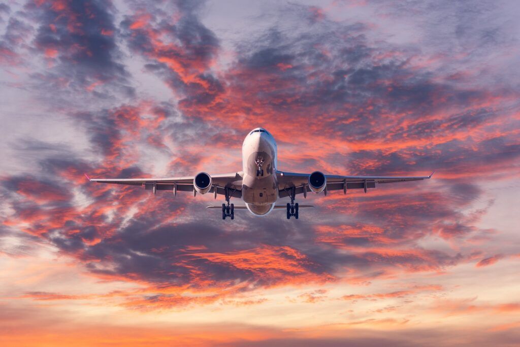 Landing passenger airplane at colorful sunset